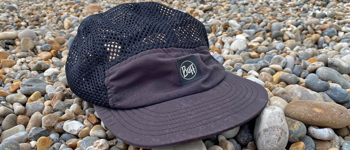 The Buff 5-Panel Air Cap on a pebbly beach.