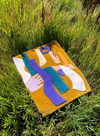 A colorful rug by Alex Proba laying on grass