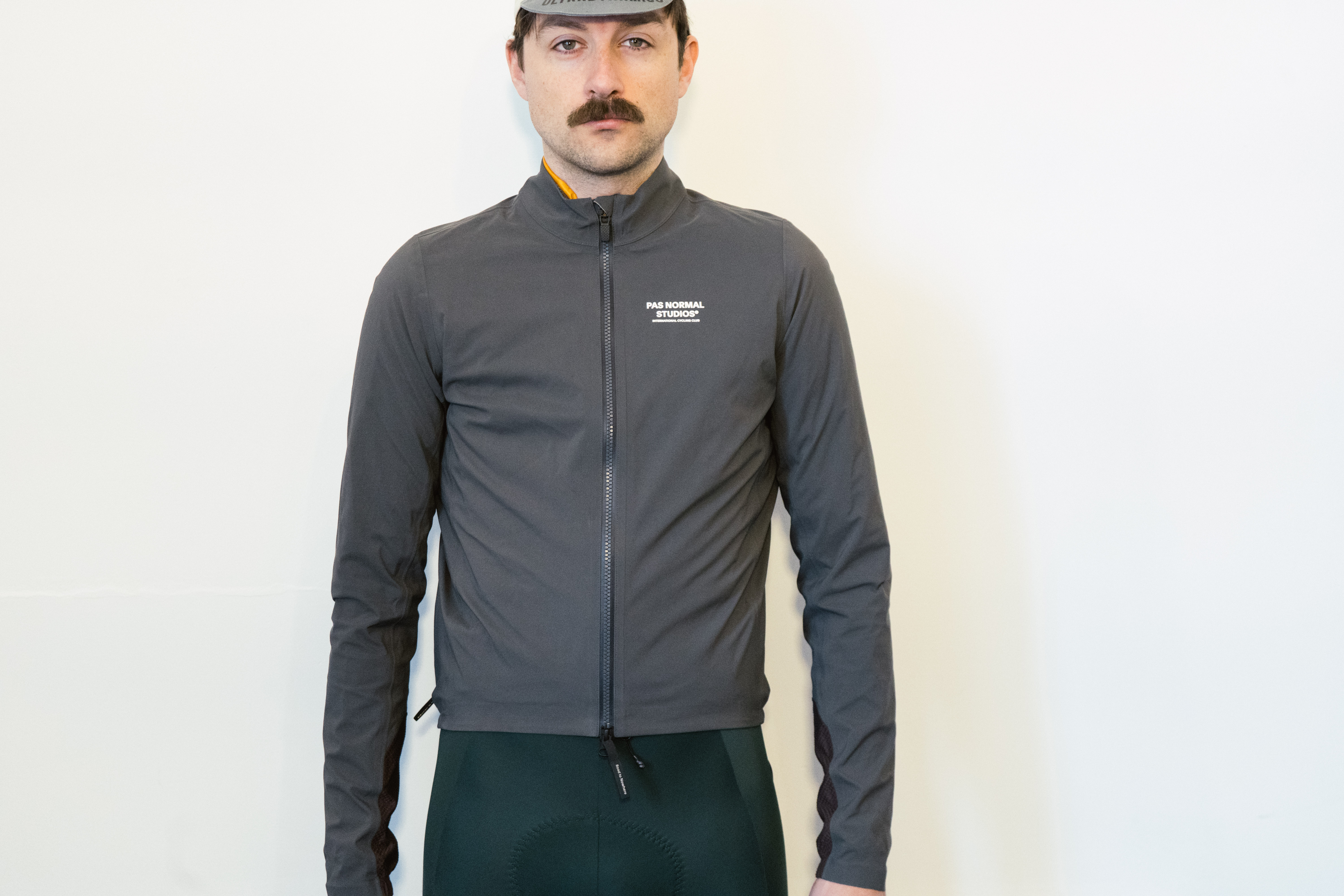 A man in a grey waterproof jacket against a white wall