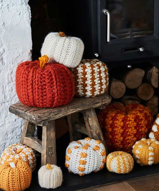 Selection of knitted pumpkins on a stool beside the stove