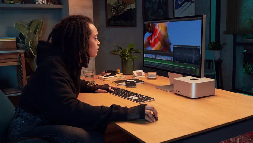 A woman using the Apple Studio Display while sitting at a desk