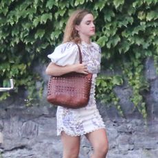 Emma Watson wears a while floral minidress with brown strappy sandals.