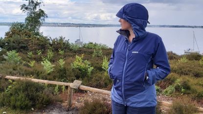 Woman wearing Paramo Velez waterproof jacket, with harbour in the background