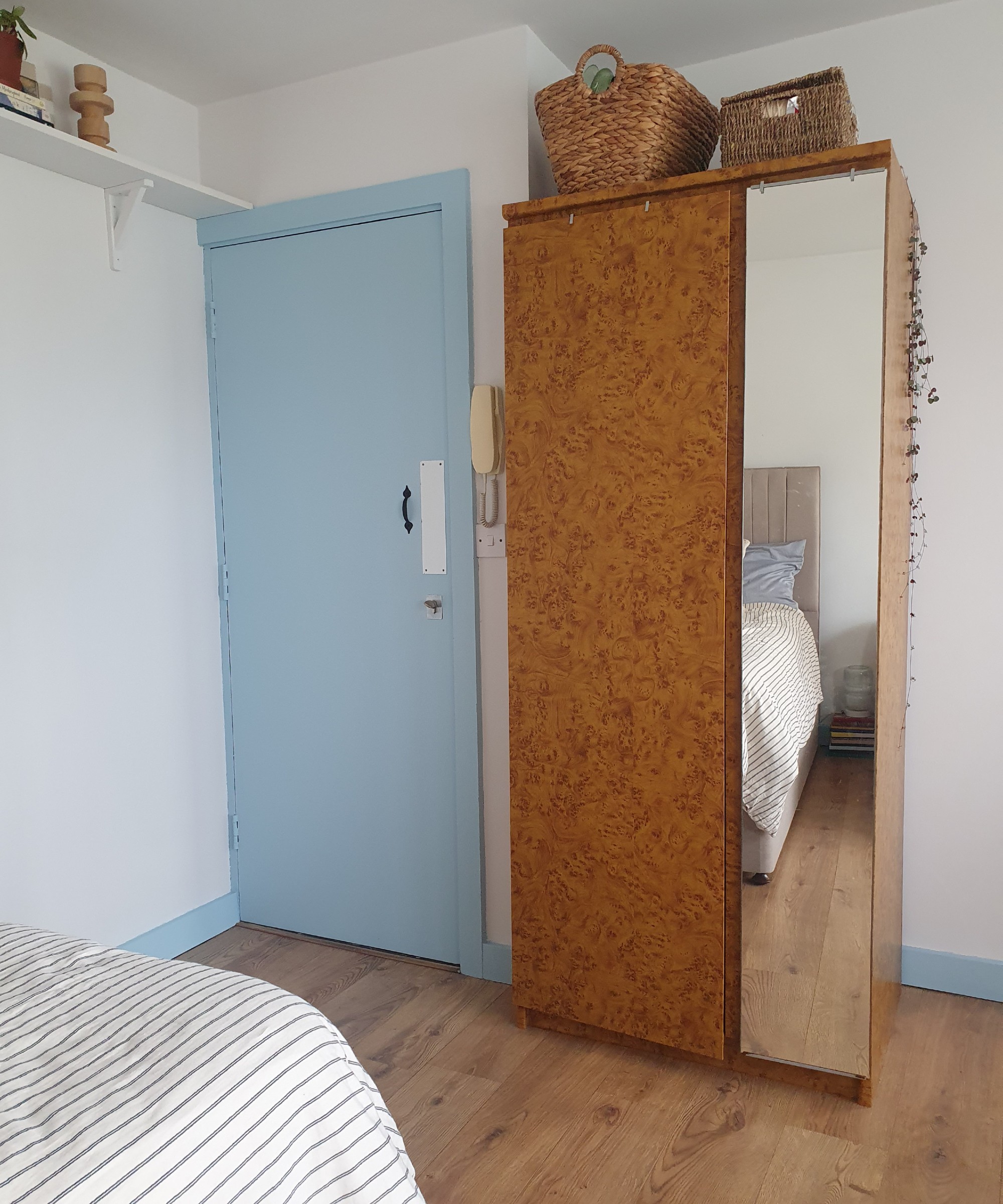 Front door painted in soft sky blue with matching skirting boards and a wardrobe covered in a burl wood-effect vinyl wrap
