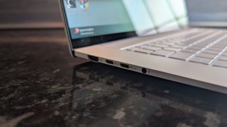 The Zenbook S 16 photographed on a dark marble surface with potted plants in the background.