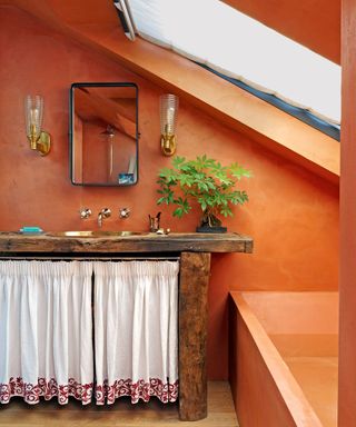 Small bathroom with orange painted walls, basin and curtain with skylight