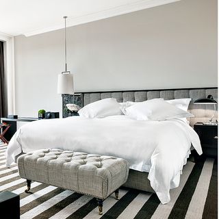 hotel room with textured wood floor and grey bed