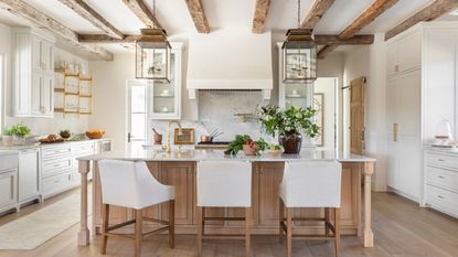 A white kitchen with a wooden island to complement the ceiling beams