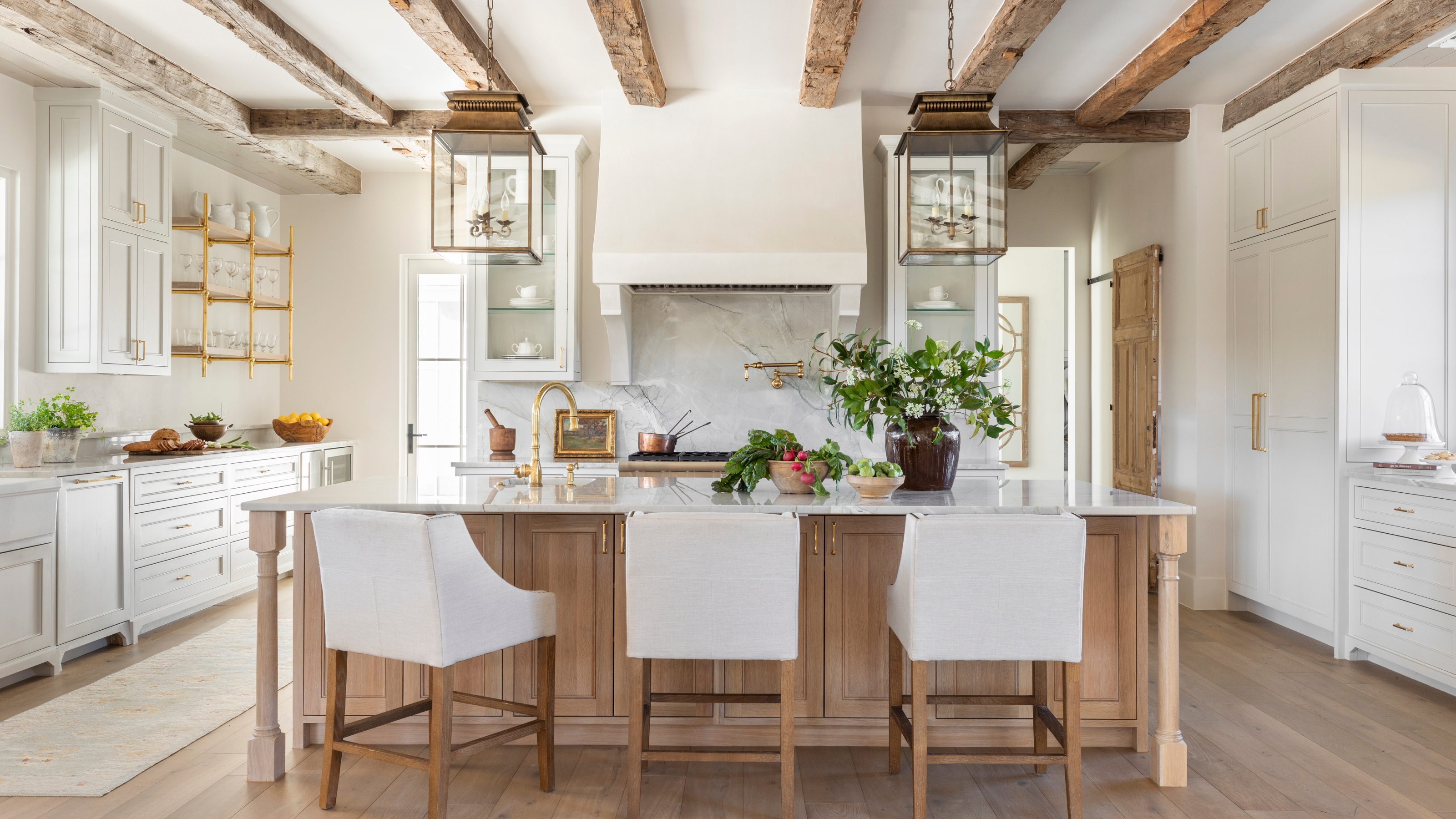 A white kitchen with a wooden island to complement the ceiling beams