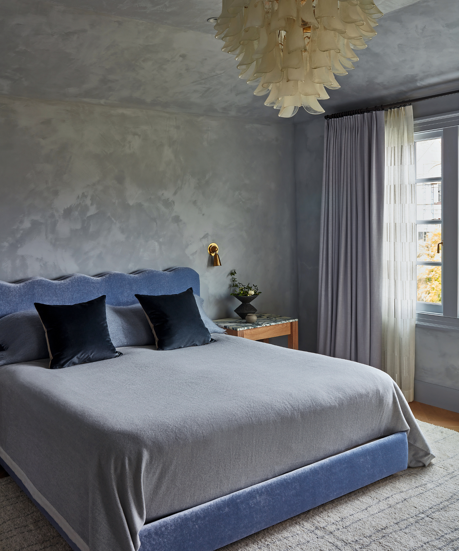 bedroom with purple bedrame with scalloped edge and limewash light purple walls and dramatic art deco ceiling pendant light