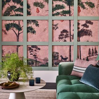 Living room with pink mural covered with green panelling in front of coffee table and green sofa
