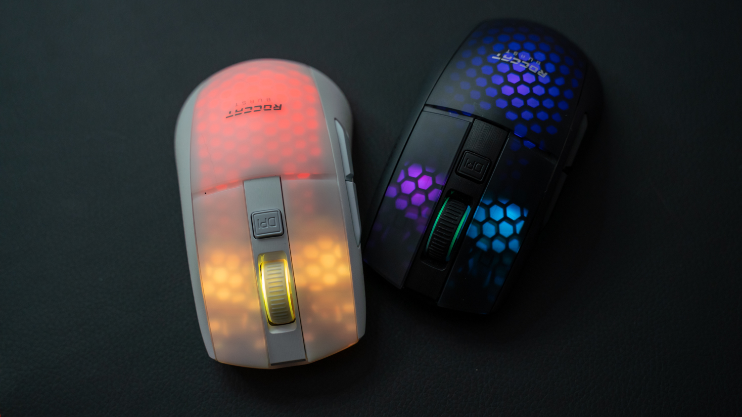 Två stycken Roccat Burst Pro Air ligger mot en mörk yta med RGB-belysningen aktiv