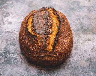 a baked sourdough loaf with a dark crust.