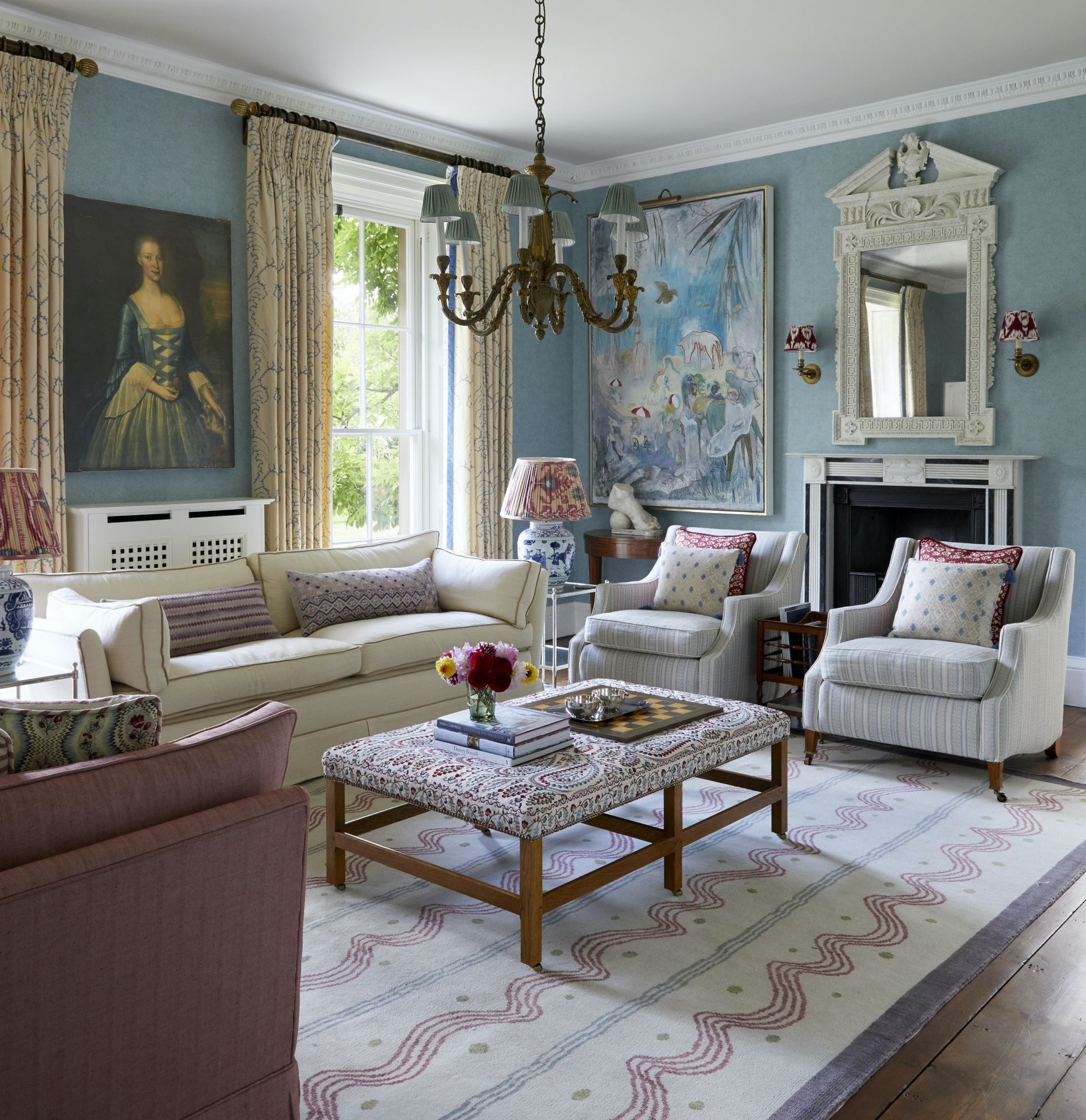 Blue wallpaper, white framed mirror and fireplace