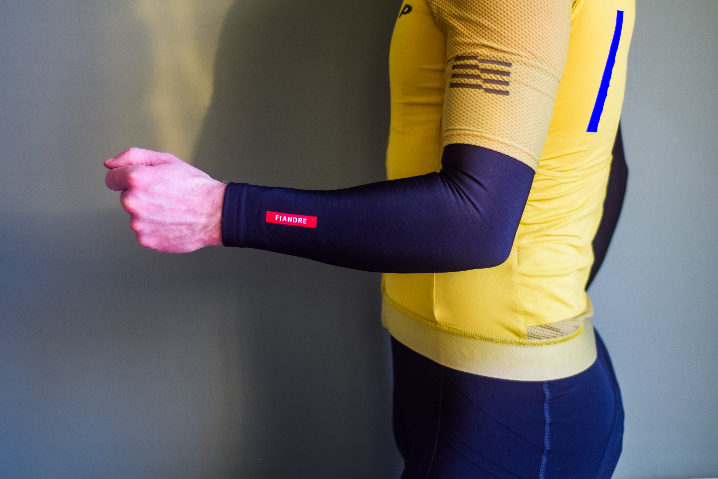 A man in a yellow cycling jersey wearing black arm warmers