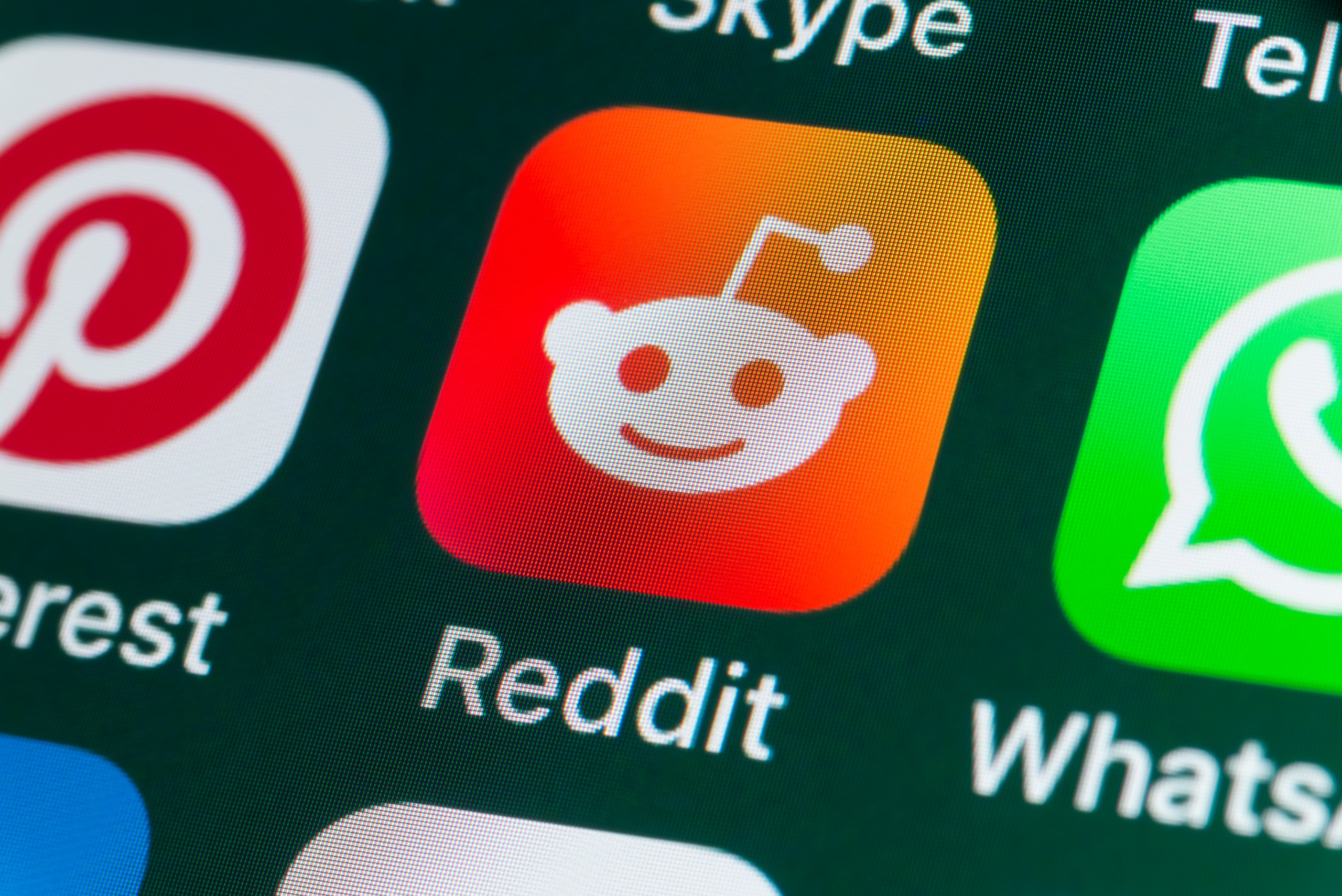 The buttons of the app Reddit, surrounded by Pinterest, Whatsapp, and other apps on the screen of an iPhone.