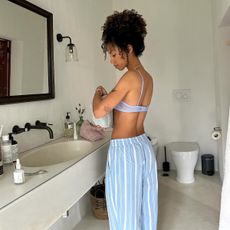 Content creator Amaka Hamelijnck standing in a bathroom with beauty products