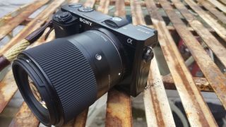 Photograph of Sony A6000 camera on metal table with 30mm lens and wrist strap