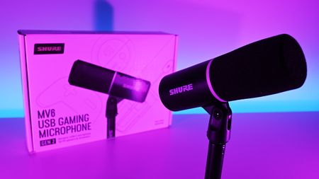 Shure MV6 Gen 2 microphone and retail box illuminated under vibrant pink and purple studio lighting.