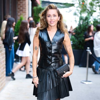 Miley Cyrus wearing a leather top and a voluminous side part hairstyle 