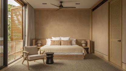 A bedroom with lime wash walls and a large window