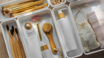 A set of acrylic drawer organziers on a white tabled filled with bathroom tools