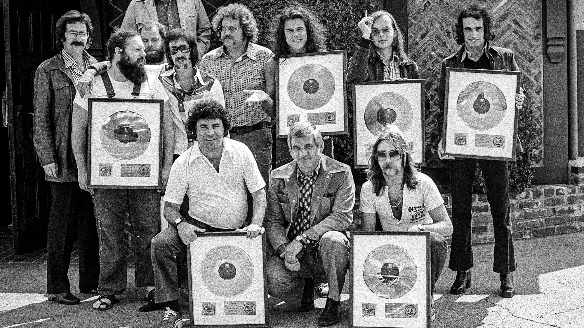 LOS ANGELES - 1973: Front Row L-R: (kneeling) Joel Cohn, Manager; Marv Helfer, Manager, Jeff Skunk Baxter, Second Row L-R: (standing) Howard Rose, booking agent; Denny Dias; Bob Gibson, Publicist; Gary Katz, Producer; Dennis Lavinthol, Sr. VP Promotions ABC Dunhill Records; Jim Hodder, Walter Becker, Donald Fagen, Top row (standing with arms outstretched) Jay Lasker, Presisdent ABC/Dunhill Records at the gold record presentation to rock band Steely Dan for the song &amp;quot;Can't Buy A Thrill&amp;quot; at ABC/Dunhill Records in 1973 in Los Angeles, California.