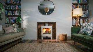 cream wood burning stove recessed into fireplace opening in living room with 2 large sofas and bookshelves in alcoves to side of fireplace