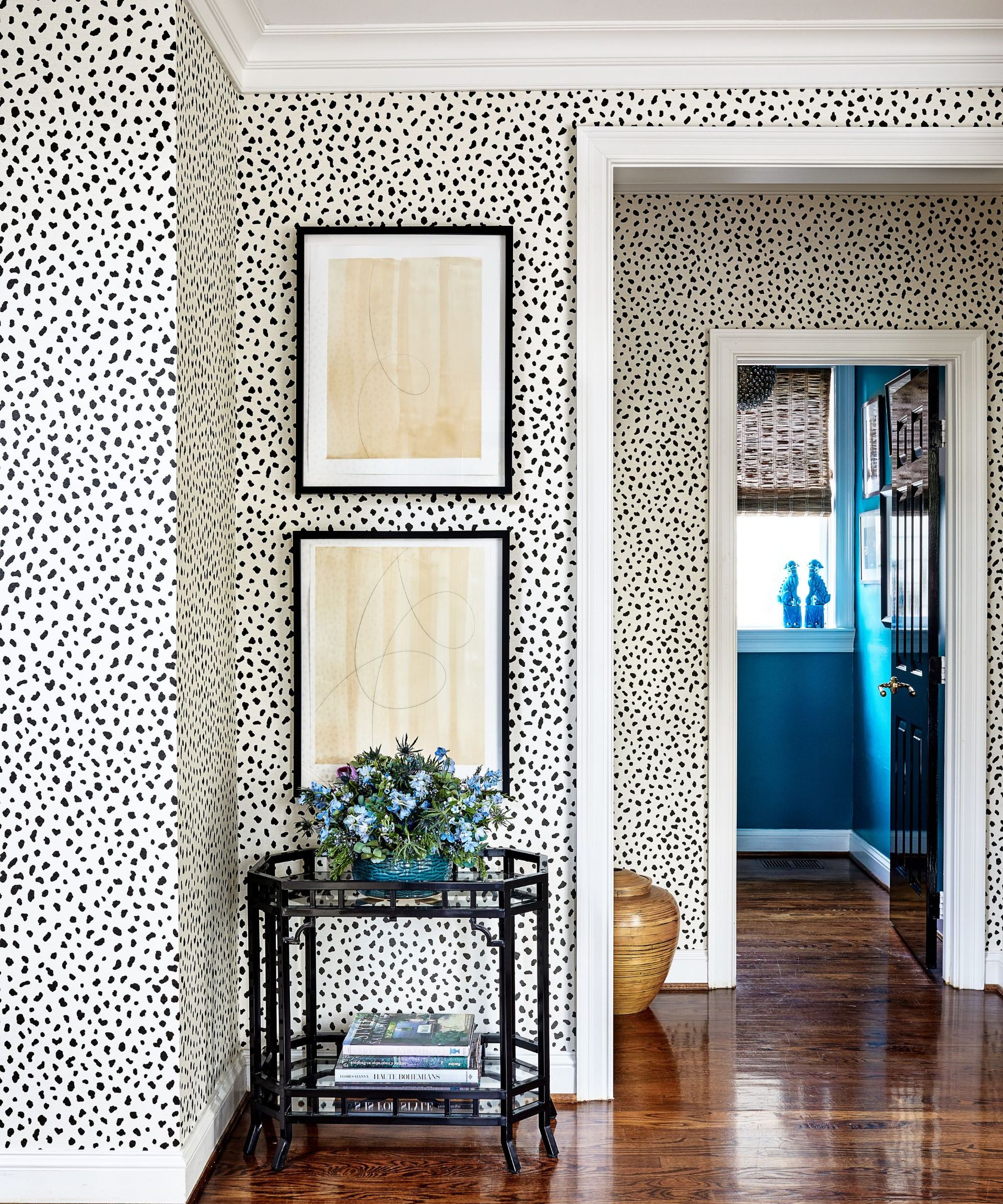 Hallway with polka dot wallpaper and wood flooring and side table with flowers and books