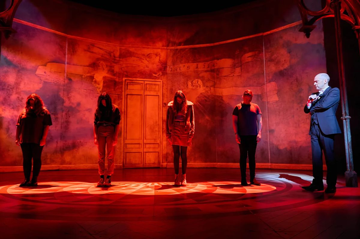 Derren Brown: Showman - four participants on stage with their heads down next to Derren