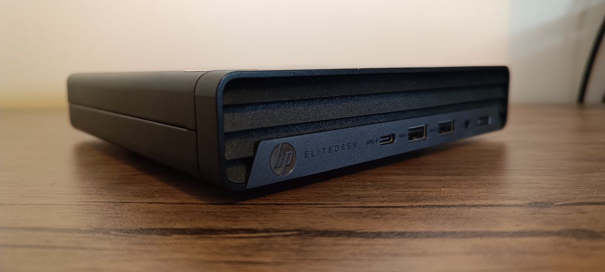 A black compact HP EliteDesk 800 desktop PC sitting on a brown wooden table