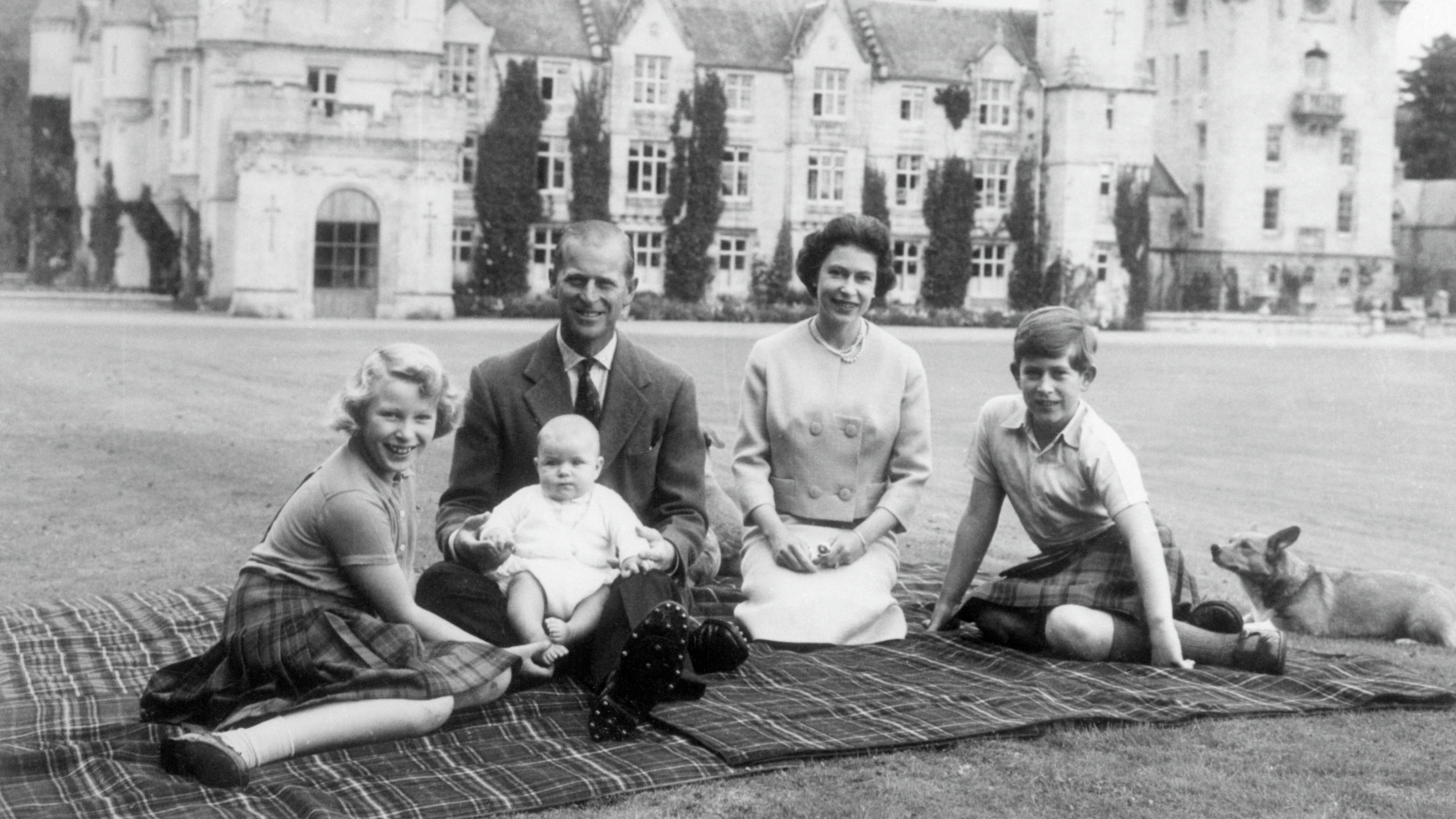 Queen Elizabeth II and Prince Philip with their children Andrew (centre), Anne (left) and Charles sitting on a picnic rug outside Balmoral Castle in Scotland, 8th September 1960