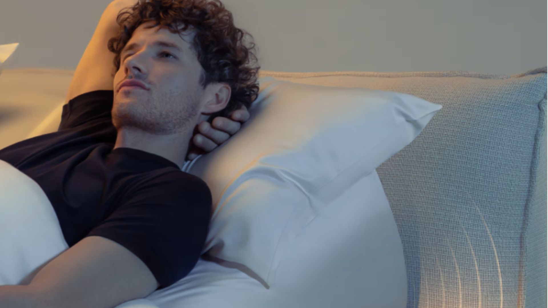 A man laying on back in bed with arm stretched behind head on Eight Sleep Pod 5 Ultra