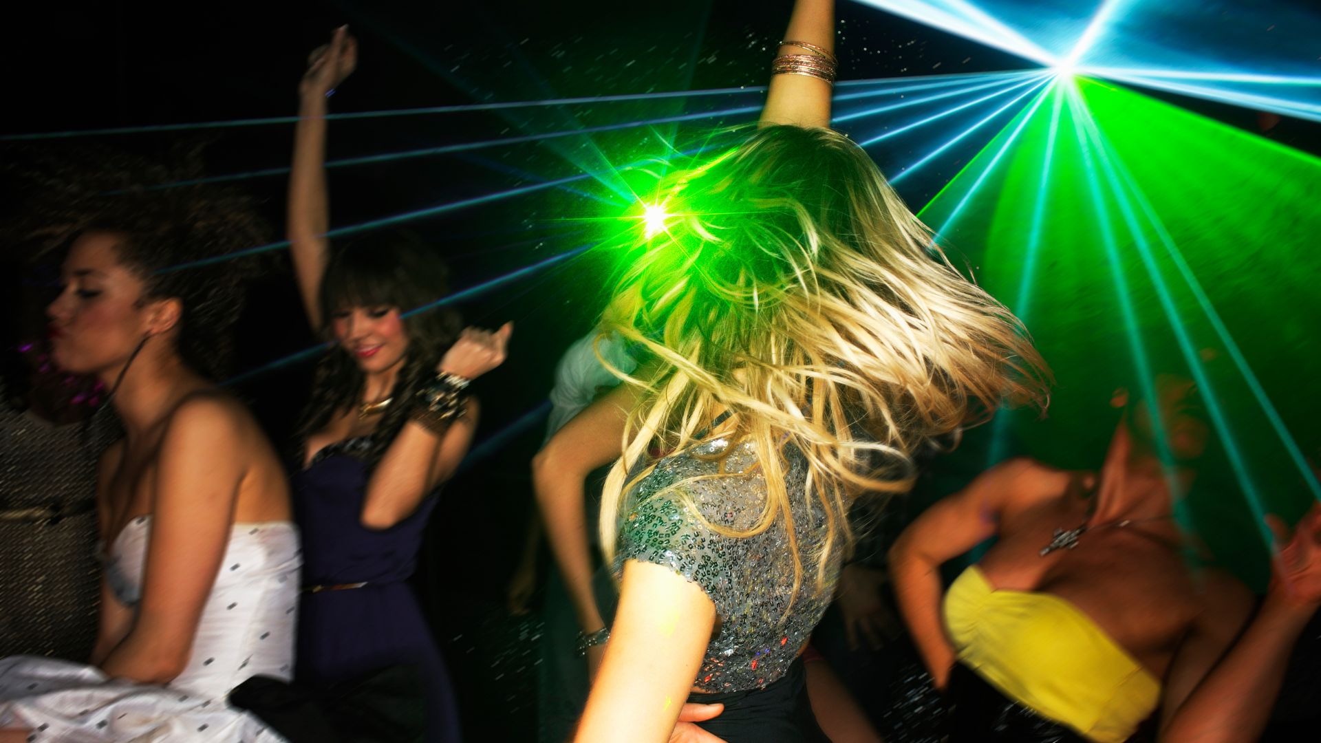 Group of young people dancing in nightclub with laser lighting.