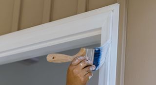 Painter painting a doorframe in bright white