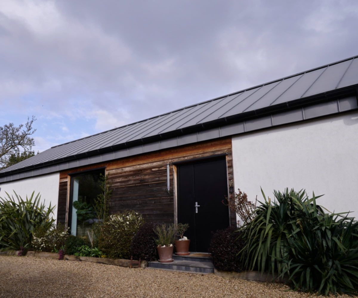 The front door of a self build with charred wooden clad front and a black door