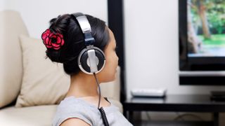 person wearing headphones in front of TV