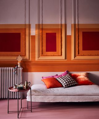 What is bauhaus style, pink and orange living room with paint blocks over wall paneling, pink couch, pink floor, metal side table