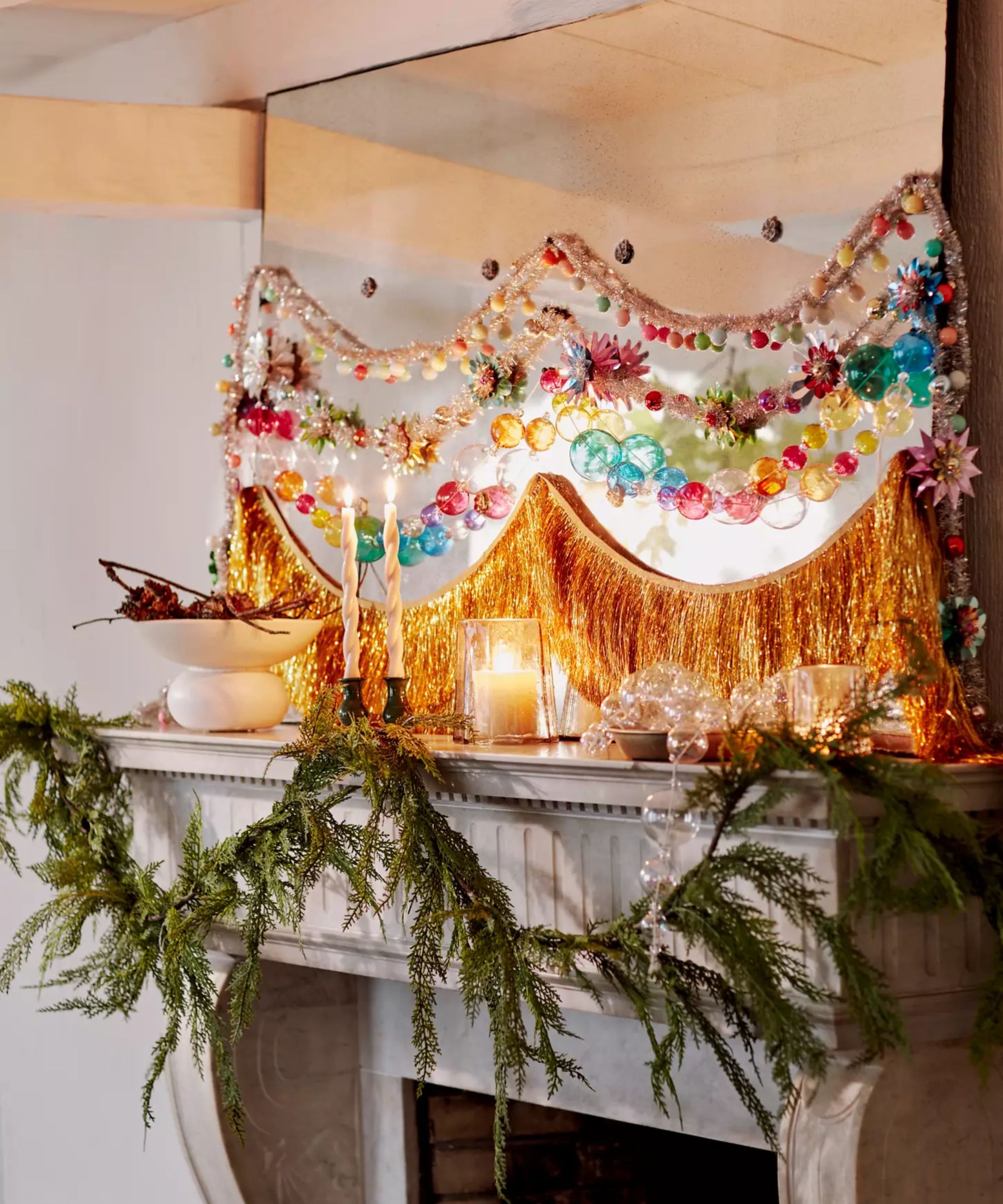 a mantel decorated with garland, tinsel decor, and other colorful garland strands