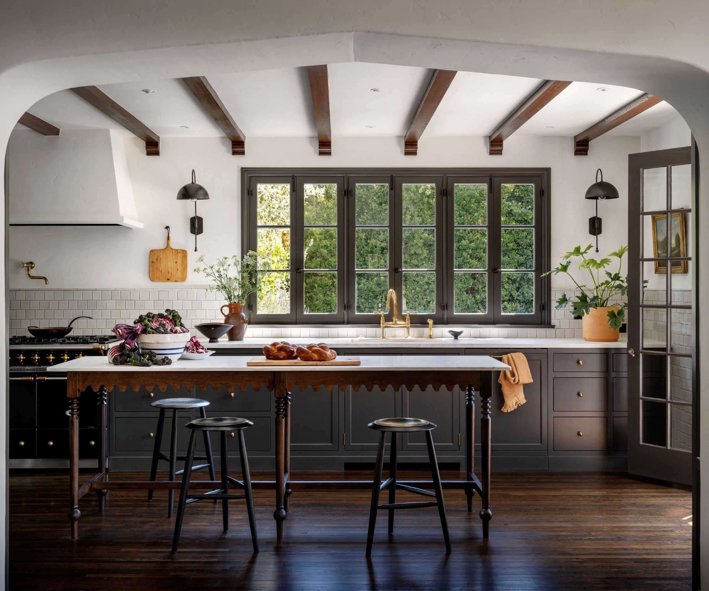 A kitchen with warm black cabinets, white walls, a dark wood floor, and a kitchen island.