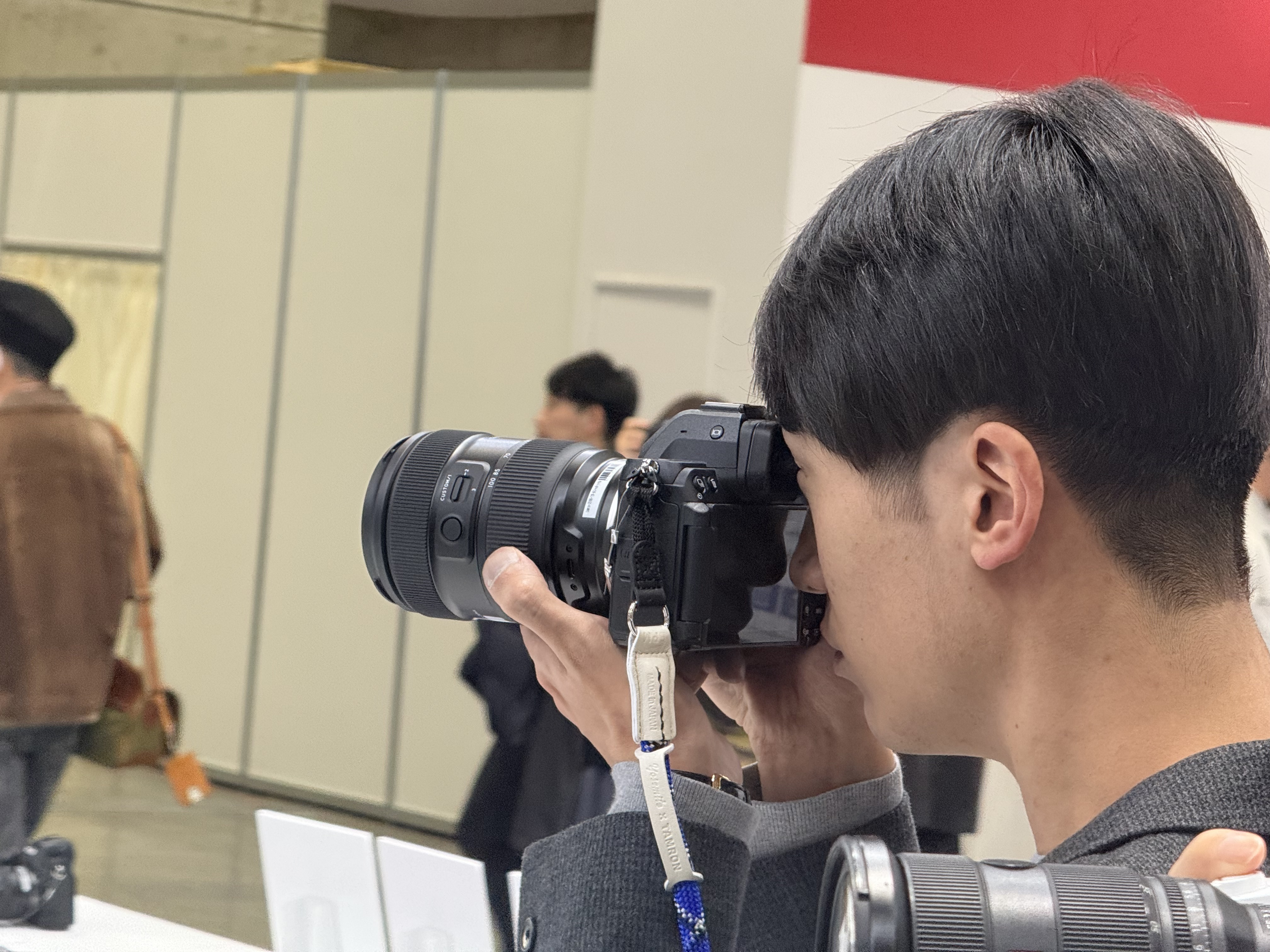 CP+ 2026 show visitor trying the Tamron 35-100mm f/2.8 zoom lens, attached to a Nikon camera