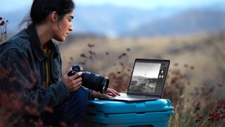 A photographer using a MacBook Pro in the field.
