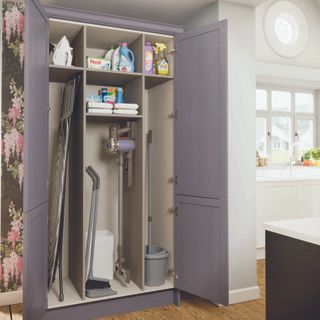 utility cupboard with ironing board and vacuum in