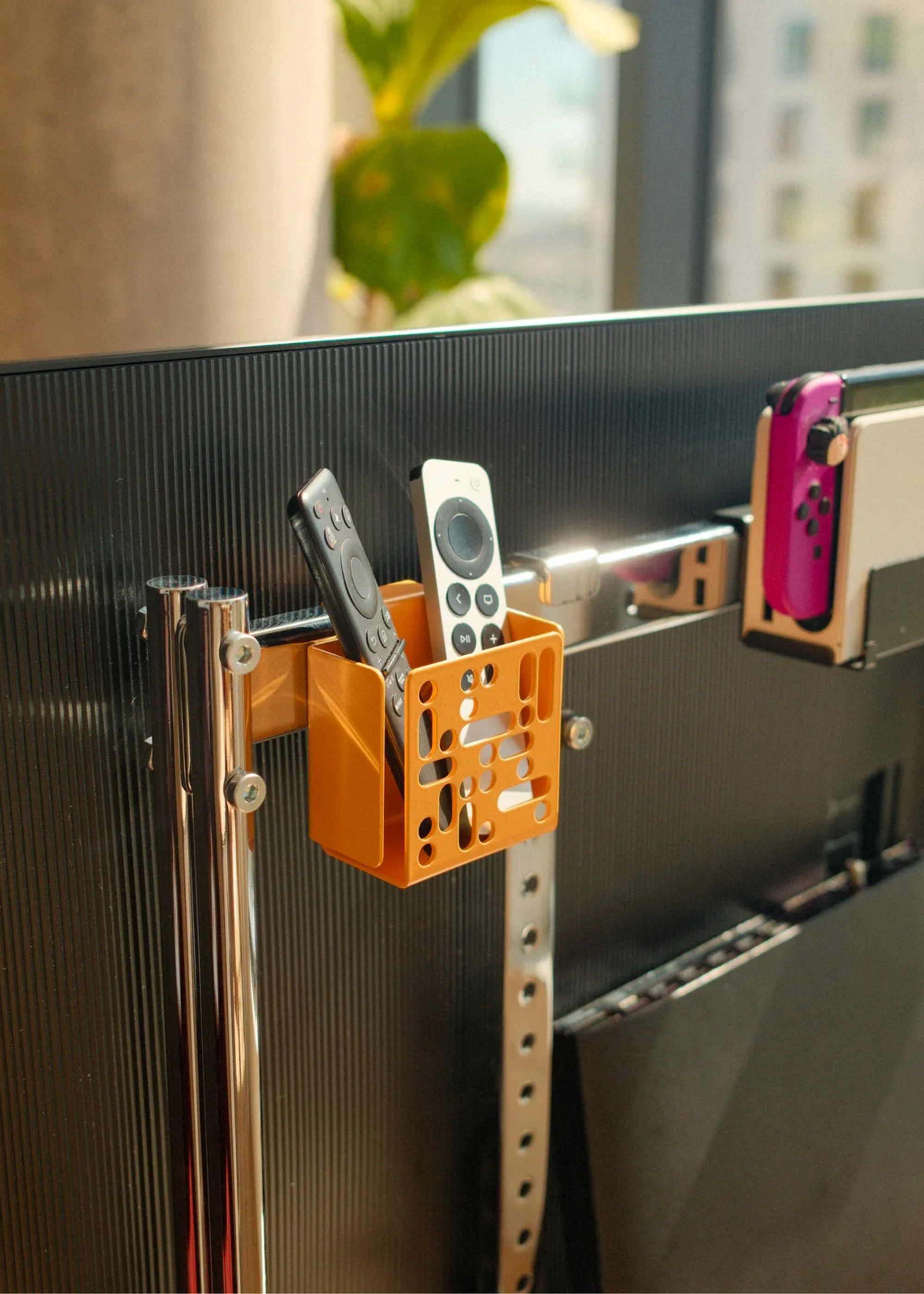 A Tv with an orange remote holder at the back