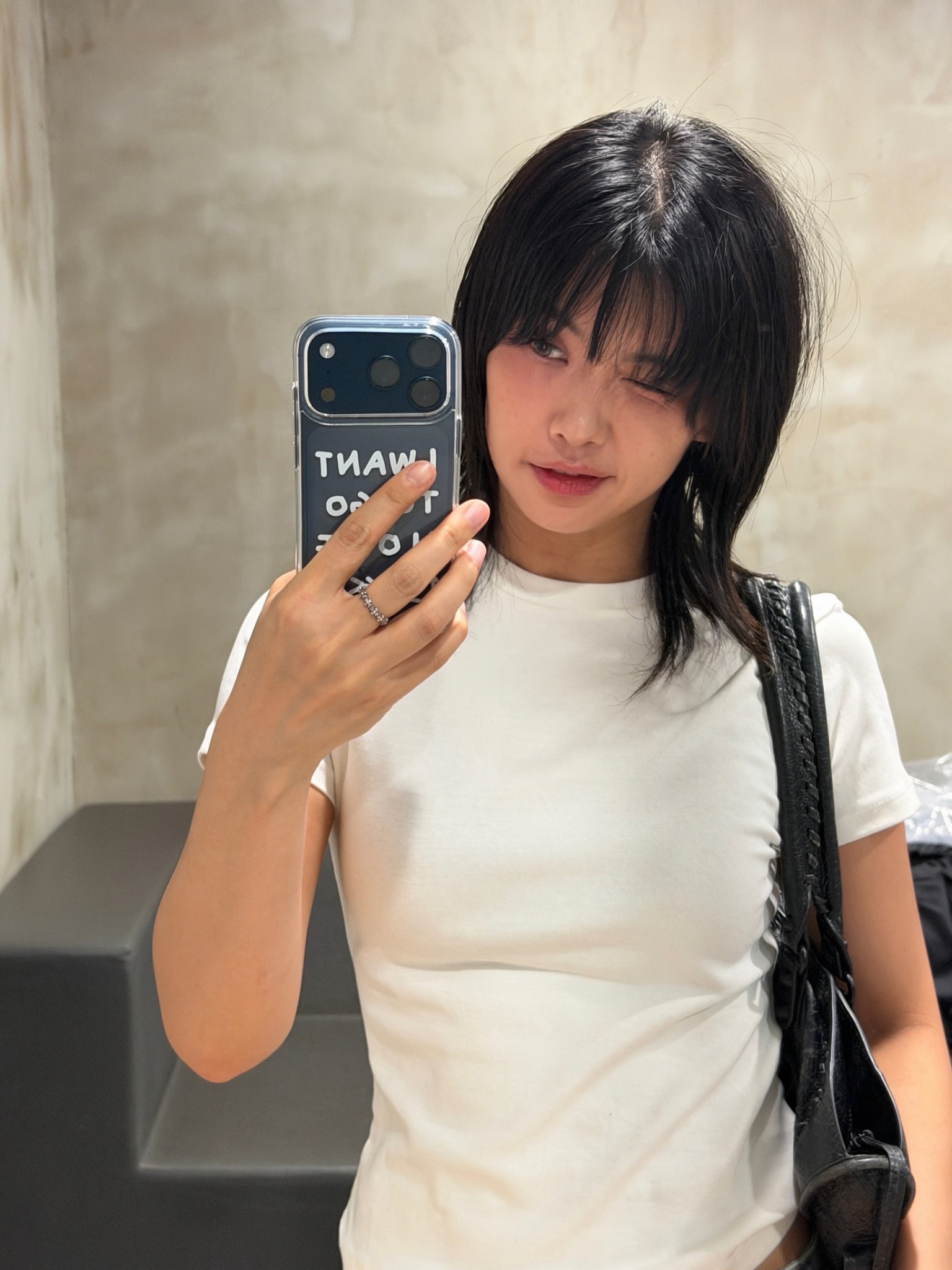 A woman with a shag haircut taking a selfie in a mirror.