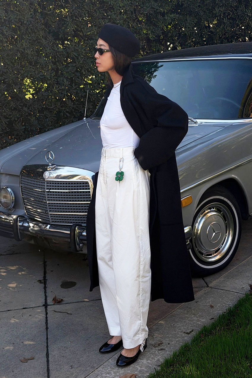 a woman wearing a long cardigan, white t-shirt, white pants, and black flats