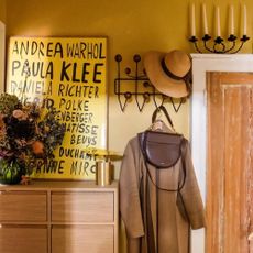 hallway with yellow wall and hooks for coat