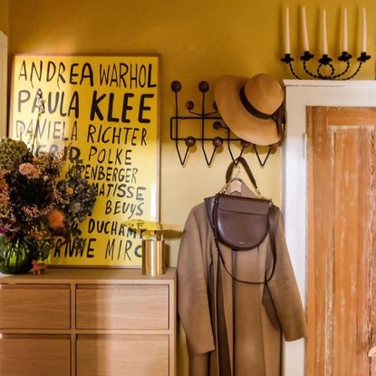 hallway with yellow wall and hooks for coat