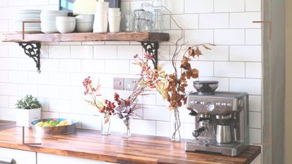 white kitchen with metro tiles and wooden worktops with a coffee machine on the side