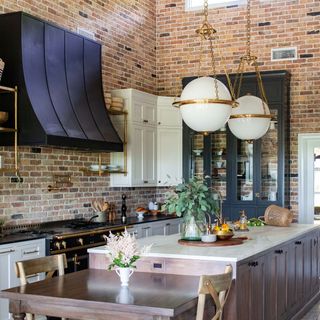 Vintage brick backsplash in brick kitchen with trad features, island and table with large spherical overhead lighting
